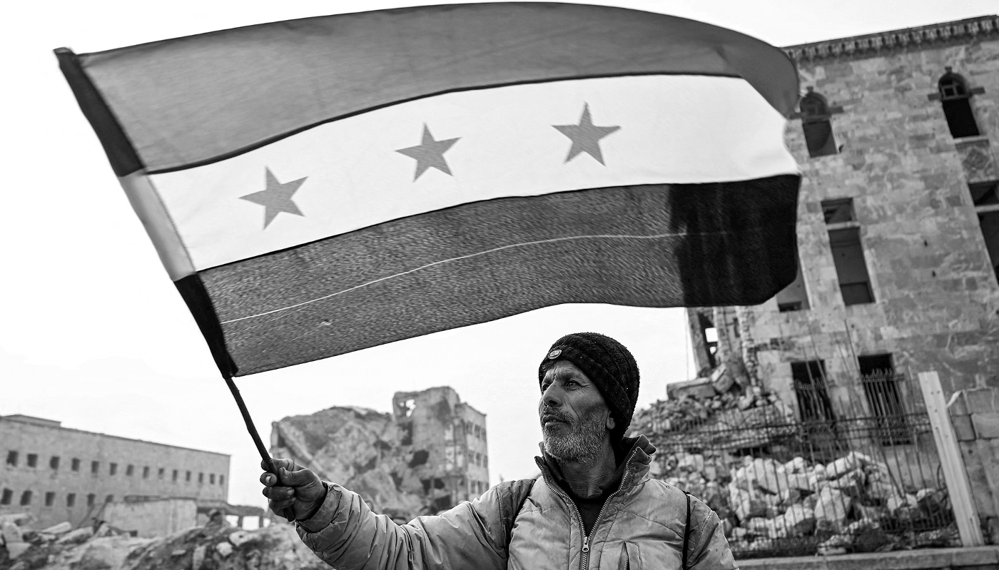A man waves a Syrian opposition flag in the citadel of Aleppo on 11 December 2024. Islamist rebels took the city on 30 November.