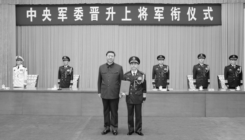 Xi Jinping presents a certificate of order to promote He Hongjun, deputy executive director of the CMC's political work department, to the rank of general.